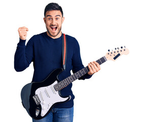 Young handsome man playing electric guitar screaming proud, celebrating victory and success very excited with raised arms