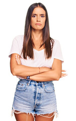 Young hispanic woman wearing casual white tshirt skeptic and nervous, disapproving expression on face with crossed arms. negative person.