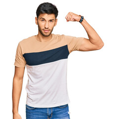 Young handsome man wearing casual clothes strong person showing arm muscle, confident and proud of power