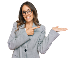Young brunette woman wearing business clothes amazed and smiling to the camera while presenting with hand and pointing with finger.