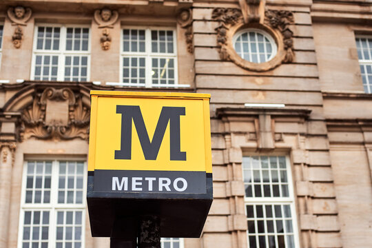 Newcastle, England, 20 August 2022: Tyne and Wear Metro rapid transit system sign. Uk Metro. A yellow sign at the top of the pillar. Station Monument.