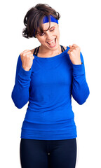 Beautiful young woman with short hair wearing training workout clothes excited for success with arms raised and eyes closed celebrating victory smiling. winner concept.