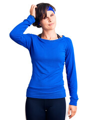 Beautiful young woman with short hair wearing training workout clothes confuse and wondering about...