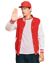 Handsome caucasian man wearing baseball uniform doing stop sing with palm of the hand. warning expression with negative and serious gesture on the face.