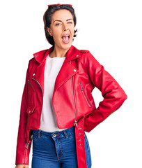 Young beautiful woman wearing red leather jacket winking looking at the camera with sexy...