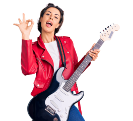 Young beautiful woman playing electric guitar doing ok sign with fingers, smiling friendly gesturing excellent symbol