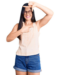 Fototapeta premium Young beautiful caucasian woman wearing casual clothes and glasses smiling making frame with hands and fingers with happy face. creativity and photography concept.