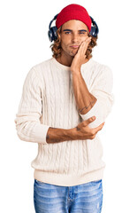 Young hispanic man listening to music using headphones thinking looking tired and bored with depression problems with crossed arms.