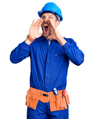 Young handsome man wearing worker uniform and hardhat angry and mad screaming frustrated and...