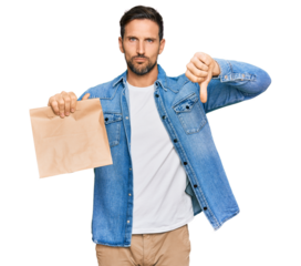 Young handsome man holding take away paper bag with angry face, negative sign showing dislike with thumbs down, rejection concept