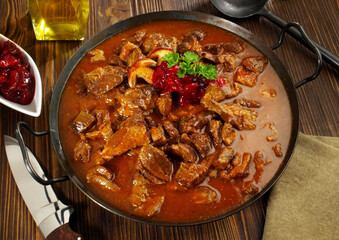 Fine Meat - Wild Game Meat Goulash in a Pan with Cranberries on wooden Background