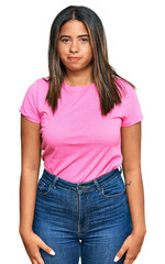 Fototapeta premium Young latin girl wearing casual clothes puffing cheeks with funny face. mouth inflated with air, crazy expression.