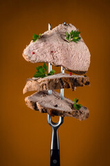 Sliced baked meat with dill and spices on a fork. Menu concept for hotel or restaurant. Organic food