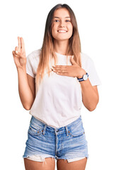 Beautiful caucasian woman wearing casual white tshirt smiling swearing with hand on chest and...