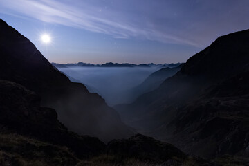 Moon rising behind Alps above misty veil