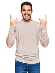 Fototapeta premium Young hispanic man wearing casual clothes shouting with crazy expression doing rock symbol with hands up. music star. heavy concept.