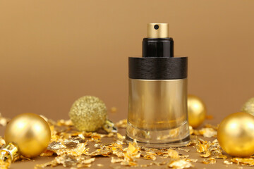 Obraz na płótnie Canvas Unbranded black and gold perfume spray bottle, gold christmas balls and paper firecracker pieces on golden background. Mockup, close-up. Bottle for branding and label, front view, new Year party