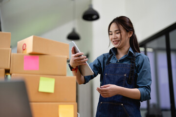 Young attractive asian woman owner startup business with box at home prepare parcel delivery in sme...