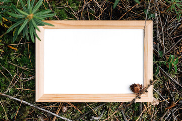 Wooden frame with white blank card on green natural background in forest. Top view Flat lay Mockup