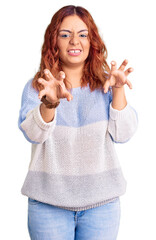 Young latin woman wearing casual clothes smiling funny doing claw gesture as cat, aggressive and...