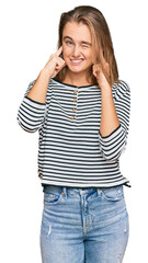 Fototapeta premium Beautiful blonde woman wearing casual clothes covering ears with fingers with annoyed expression for the noise of loud music. deaf concept.