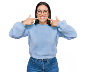 Young hispanic woman wearing casual clothes and glasses smiling cheerful showing and pointing with fingers teeth and mouth. dental health concept.