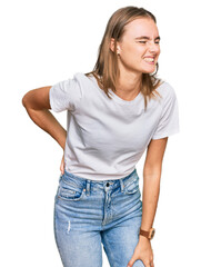 Fototapeta premium Beautiful young blonde woman wearing casual white t shirt suffering of backache, touching back with hand, muscular pain