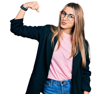 Hispanic young woman wearing business jacket and glasses strong person showing arm muscle, confident and proud of power