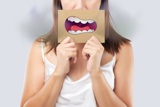 Asian woman in the red shirt holding a brown paper with the yellow teeth cartoon picture of his mouth against the gray background, Bad breath or Halitosis, The concept with healthcare gums and teeth.