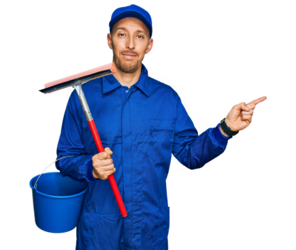 Bald man with beard wearing glass cleaner uniform and squeegee smiling happy pointing with hand and finger to the side