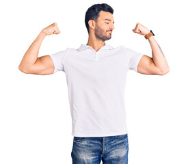 Young handsome hispanic man wearing casual clothes showing arms muscles smiling proud. fitness concept.