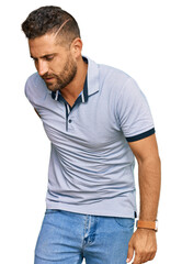Fototapeta premium Handsome man with beard wearing casual clothes suffering of backache, touching back with hand, muscular pain