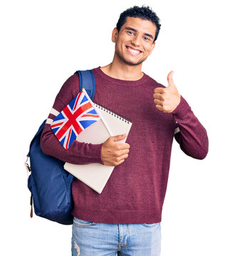 Hispanic handsome young man exchange student holding uk flag smiling happy and positive, thumb up doing excellent and approval sign