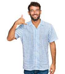 Naklejka premium Handsome young man with beard wearing casual fresh shirt smiling doing phone gesture with hand and fingers like talking on the telephone. communicating concepts.