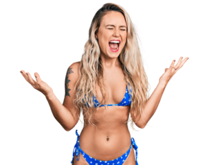 Young blonde woman wearing bikini crazy and mad shouting and yelling with aggressive expression and arms raised. frustration concept.