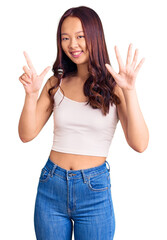 Young beautiful chinese girl wearing casual clothes showing and pointing up with fingers number seven while smiling confident and happy.