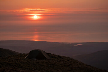 Fototapeta na wymiar A wild camping tent high in the mountains at sunset