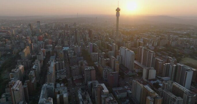 Aerial fly over view of the magnificent Johannesburg City Centre at sunset surrounded by smog and pollution.