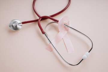 Pink ribbon and stethoscope on a pink background close-up. Breast cancer awareness concept