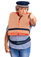 Senior woman with gray hair wearing nautical lifejacket pointing with finger to the camera and to you, confident gesture looking serious