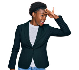 Young african american girl wearing business clothes very happy and smiling looking far away with hand over head. searching concept.