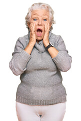 Senior grey-haired woman wearing casual winter sweater afraid and shocked, surprise and amazed...