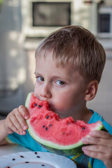 Cute boy eating watermelon at home. Real emotions without posing.