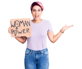 Young beautiful woman with pink hair holding woman power banner celebrating victory with happy smile and winner expression with raised hands