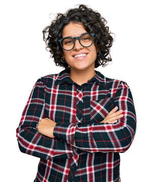 Young hispanic woman with curly hair wearing casual clothes and glasses happy face smiling with crossed arms looking at the camera. positive person.