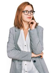 Young caucasian woman wearing business style and glasses with hand on chin thinking about question,...