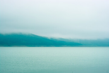 Beautiful lakeside view with fog over the forest. 