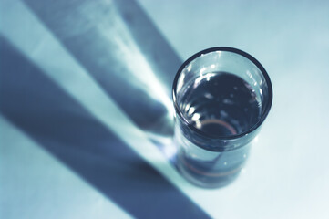 Glass of water with shadow. Minimal still life image of water.