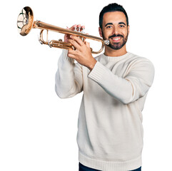 Young hispanic man with beard playing trumpet smiling with a happy and cool smile on face. showing teeth. - obrazy, fototapety, plakaty