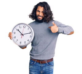 Young arab man holding big clock pointing finger to one self smiling happy and proud